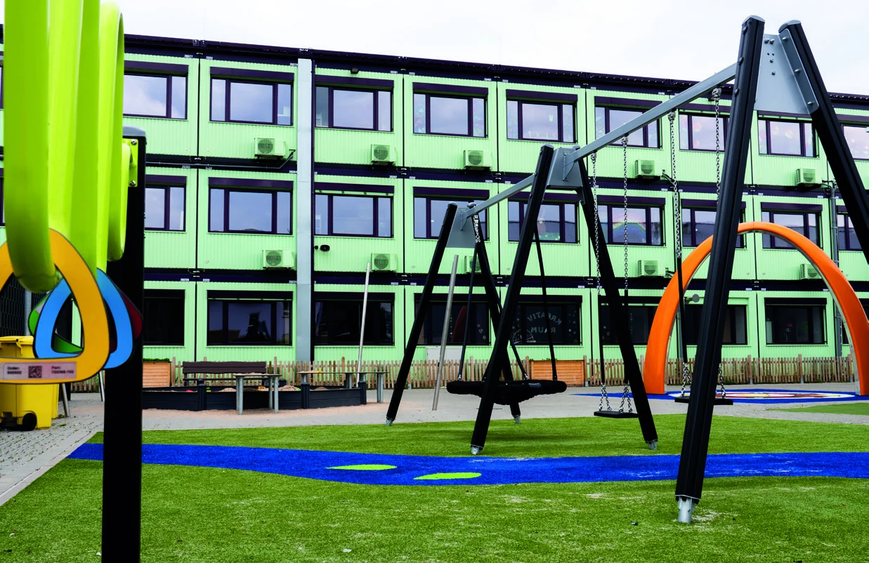 Hellgrüne Modulanlage der Levana-Schule mit Spielgeräten im Außenbereich