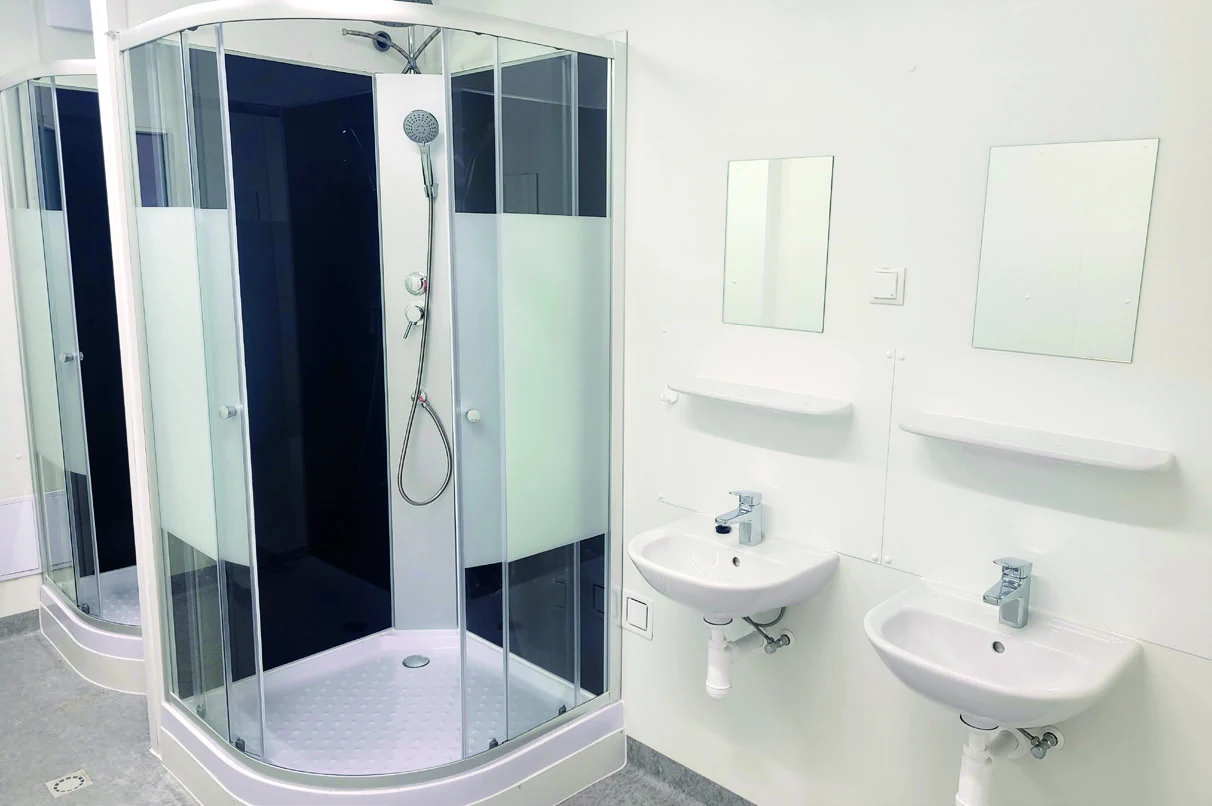 Sanitärraum einer Modulanlage mit Duschkabine, zwei Waschbecken und Spiegeln